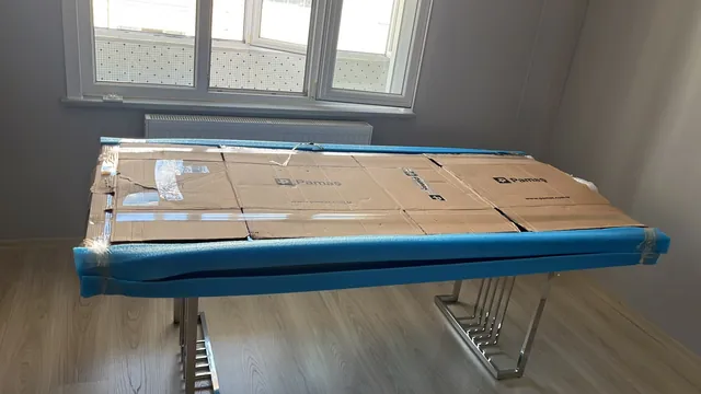 Masa yüzeyinin karton ve mavi kenar koruyucuyla ambalajlanması